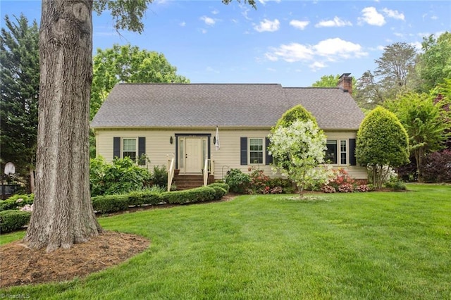 view of front of house featuring a chimney, a front lawn, and roof with shingles