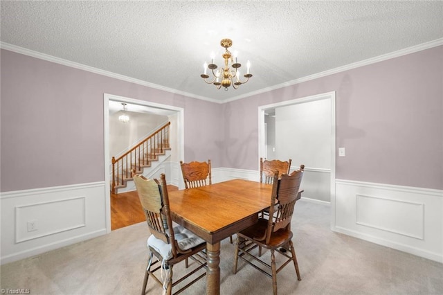 dining area featuring wainscoting, a chandelier, stairs, a textured ceiling, and ornamental molding