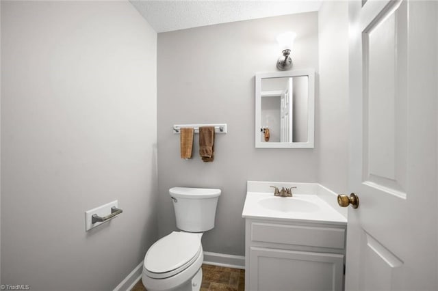 half bath featuring baseboards, vanity, and toilet