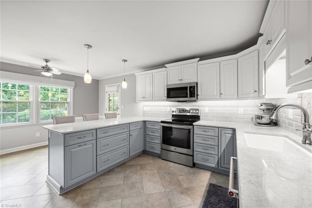kitchen featuring appliances with stainless steel finishes, gray cabinetry, a sink, backsplash, and crown molding