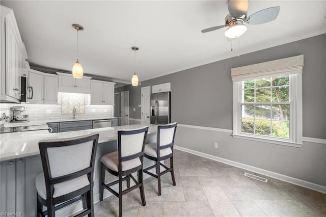 kitchen featuring stainless steel appliances, baseboards, a sink, a peninsula, and decorative backsplash