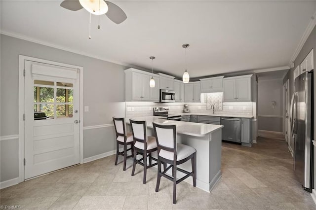 kitchen featuring appliances with stainless steel finishes, a peninsula, a sink, crown molding, and tasteful backsplash