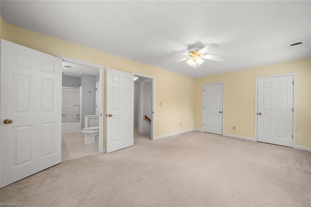 unfurnished bedroom with light carpet, baseboards, connected bathroom, and a ceiling fan