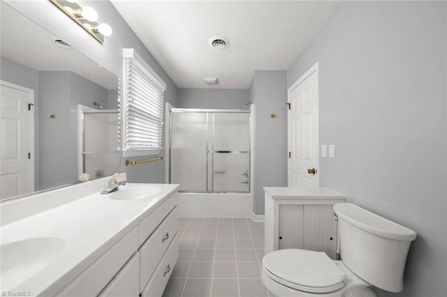 full bath featuring toilet, combined bath / shower with glass door, double vanity, a textured ceiling, and tile patterned floors