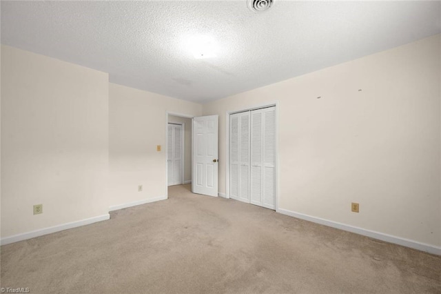 unfurnished bedroom with light carpet, baseboards, a closet, and a textured ceiling