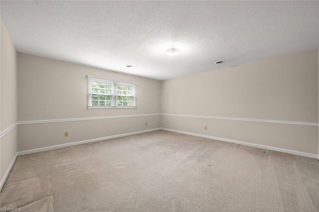 unfurnished room with light colored carpet, a textured ceiling, and baseboards