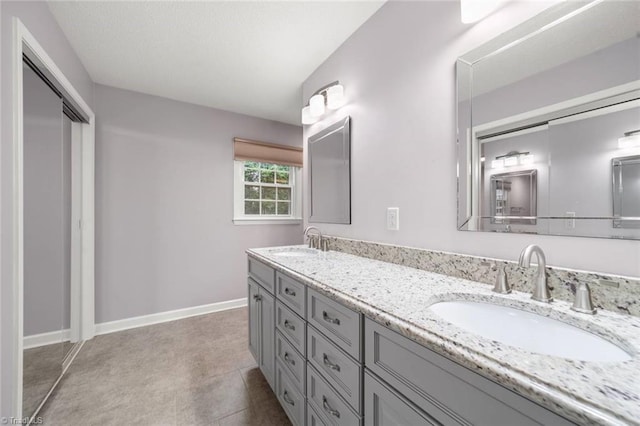 bathroom with double vanity and baseboards
