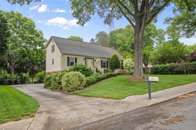 view of front of house with a chimney, driveway, and a front yard
