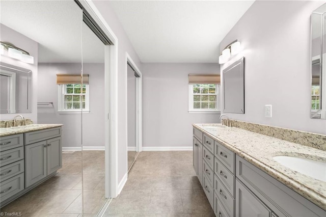 bathroom with double vanity, tile patterned floors, and baseboards