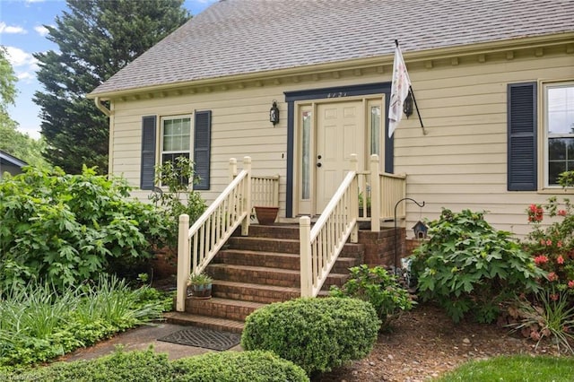 view of exterior entry with roof with shingles
