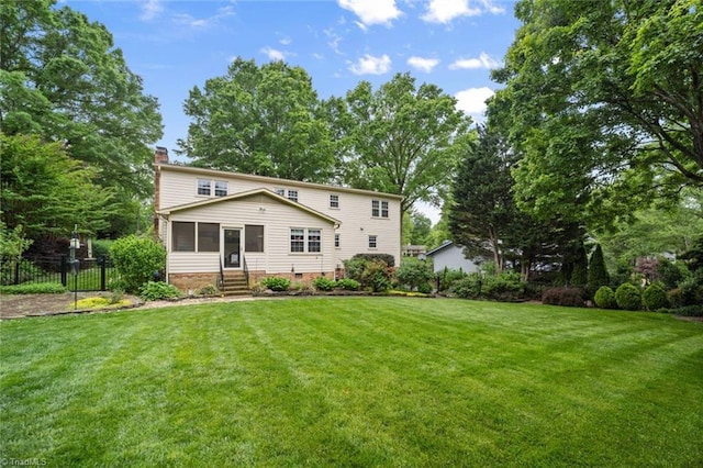 rear view of house with a chimney, entry steps, and a sunroom