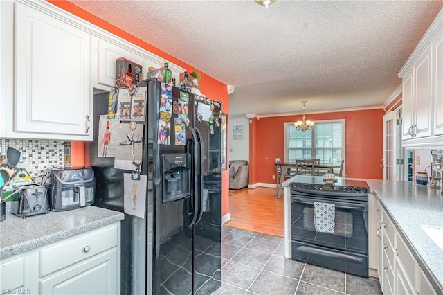 kitchen with pendant lighting, white cabinetry, tile patterned flooring, backsplash, and black appliances