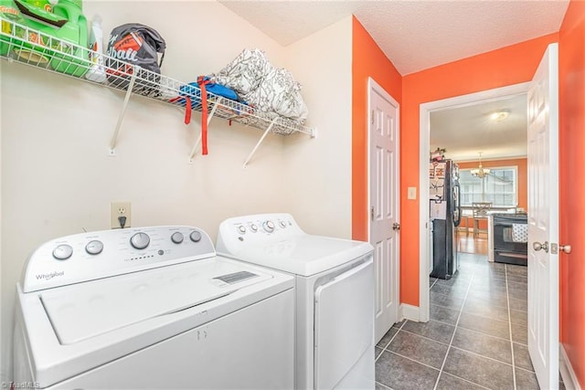 laundry area featuring dark tile patterned flooring, independent washer and dryer, and a chandelier