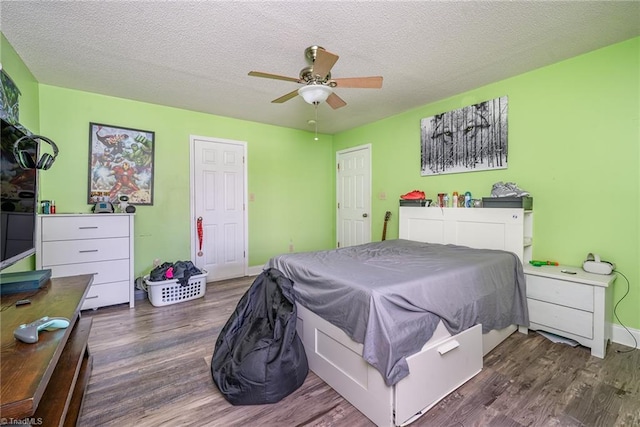 bedroom with ceiling fan, dark hardwood / wood-style flooring, and a textured ceiling