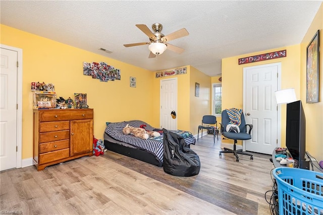 bedroom featuring ceiling fan, light hardwood / wood-style flooring, and a textured ceiling