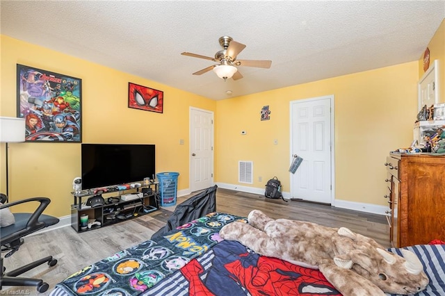 bedroom featuring ceiling fan, hardwood / wood-style floors, and a textured ceiling