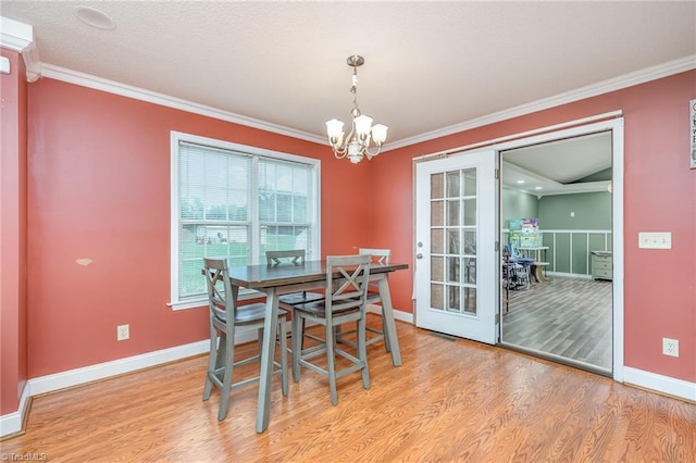 dining space featuring an inviting chandelier, ornamental molding, french doors, and light wood-type flooring