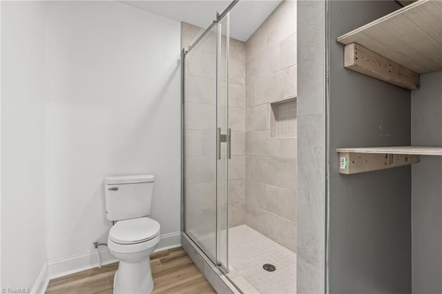 bathroom with hardwood / wood-style floors, a shower with shower door, and toilet