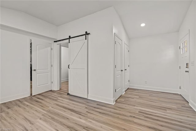 unfurnished bedroom featuring light hardwood / wood-style flooring and a barn door