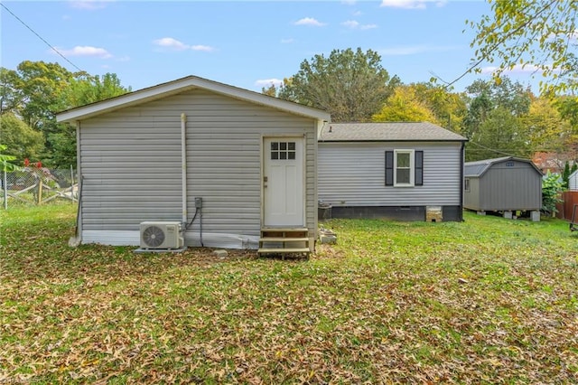 rear view of property featuring ac unit, a lawn, and a storage unit