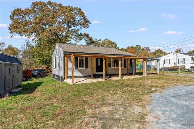 view of front facade with a patio area, a front lawn, and a storage unit