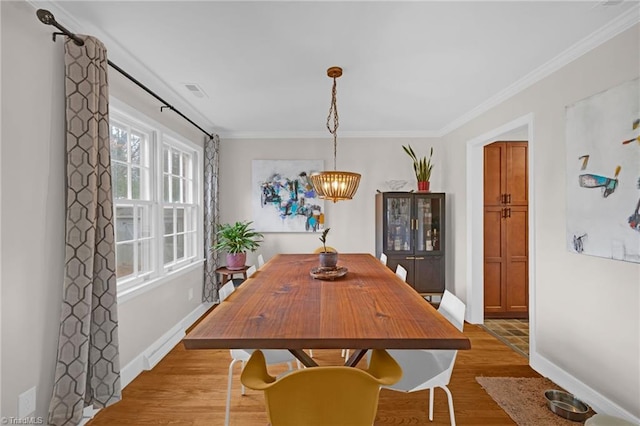 dining space featuring light hardwood / wood-style floors, an inviting chandelier, and ornamental molding