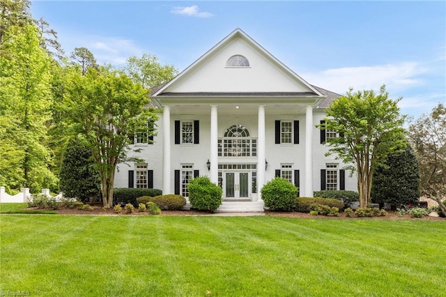 neoclassical home featuring french doors, stucco siding, and a front yard