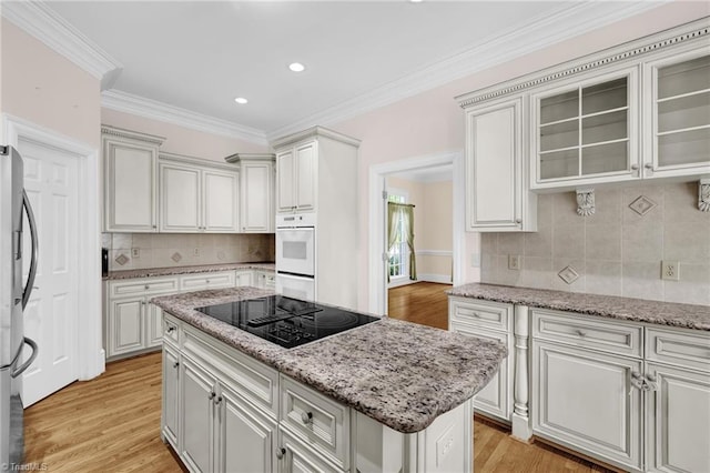 kitchen featuring decorative backsplash, light wood finished floors, black electric stovetop, and ornamental molding
