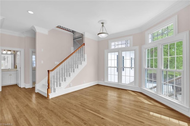 interior space with baseboards, ornamental molding, light wood finished floors, and stairs