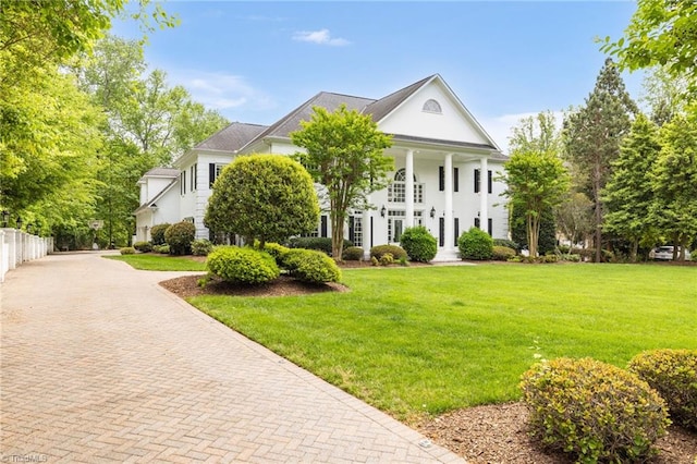 greek revival inspired property with decorative driveway and a front lawn