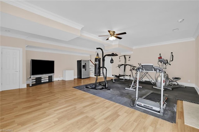 exercise room featuring crown molding, wood finished floors, baseboards, a tray ceiling, and a ceiling fan