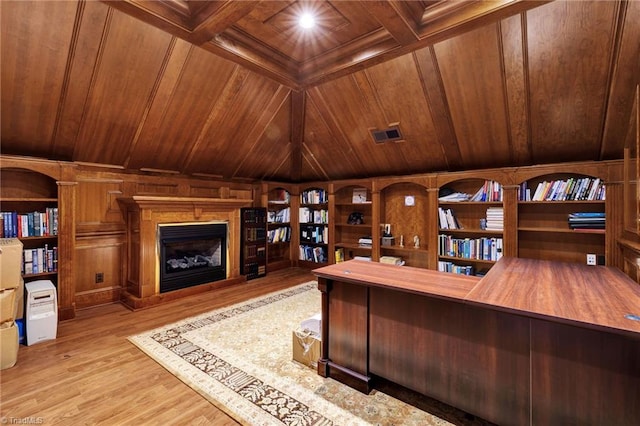 home office with wooden walls, beam ceiling, a fireplace with raised hearth, wooden ceiling, and wood finished floors