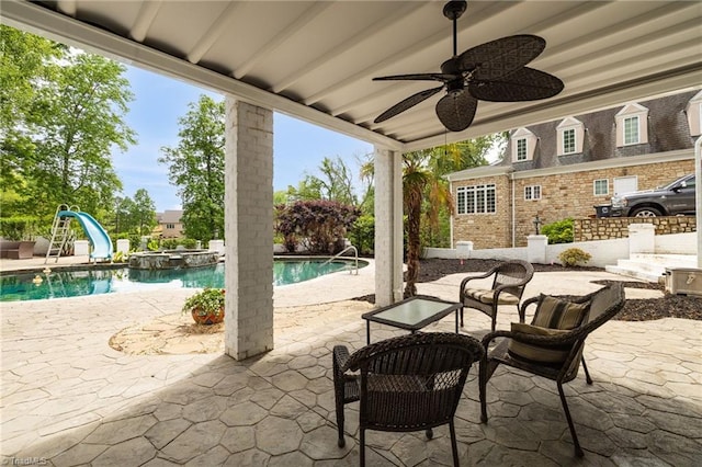 view of patio with ceiling fan, a pool with connected hot tub, and an outdoor structure