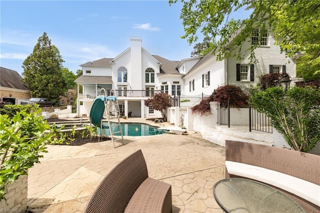 back of house with a chimney, a patio area, and an outdoor pool
