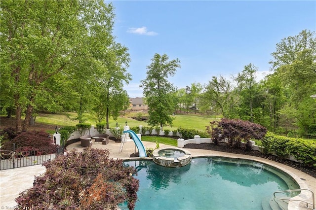 view of pool with a lawn, a patio area, a water slide, and a pool with connected hot tub