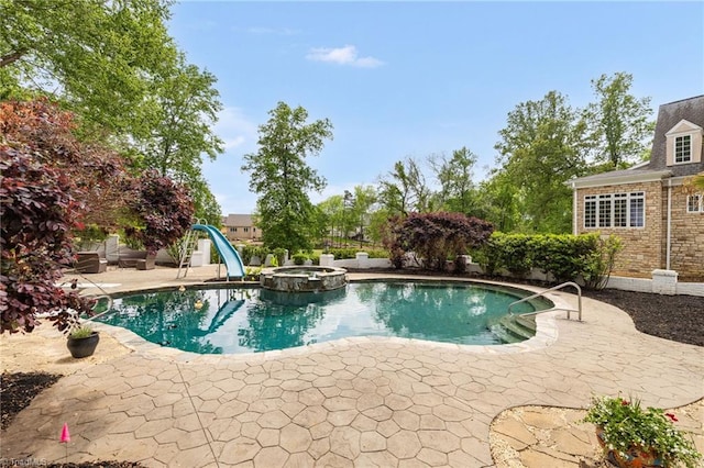 view of swimming pool featuring a patio, a water slide, and a pool with connected hot tub