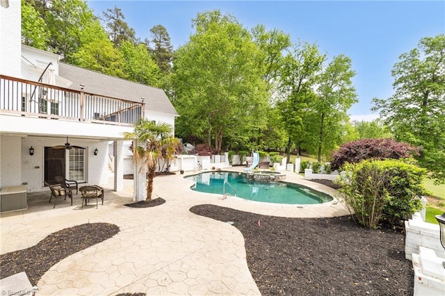 view of pool with a ceiling fan, a patio, a pool with connected hot tub, and a fire pit