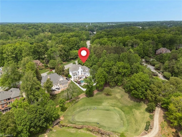 drone / aerial view with view of golf course and a wooded view