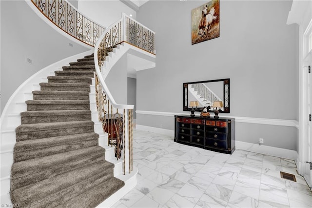 stairway with baseboards, marble finish floor, a towering ceiling, and visible vents