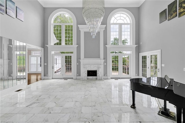 living room with a high ceiling, a notable chandelier, a wealth of natural light, and marble finish floor