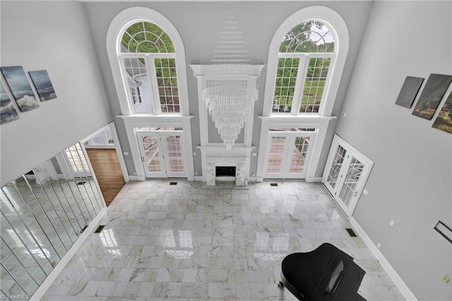 unfurnished living room featuring french doors, marble finish floor, and a towering ceiling