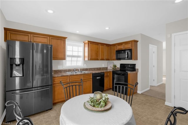 kitchen with light tile patterned floors, stone countertops, sink, and black appliances