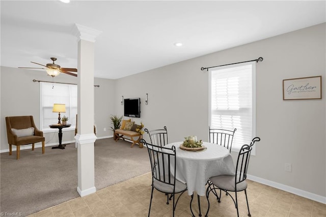 carpeted dining space with ceiling fan and ornate columns