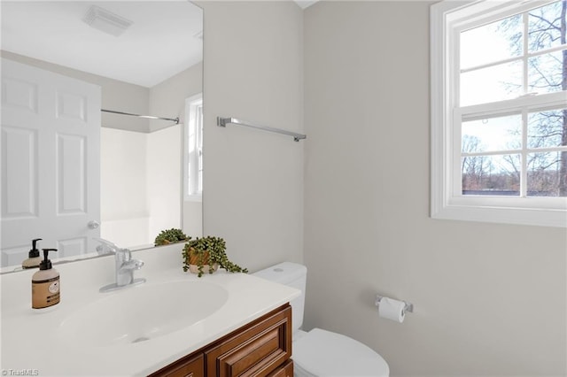 bathroom with vanity, a healthy amount of sunlight, and toilet