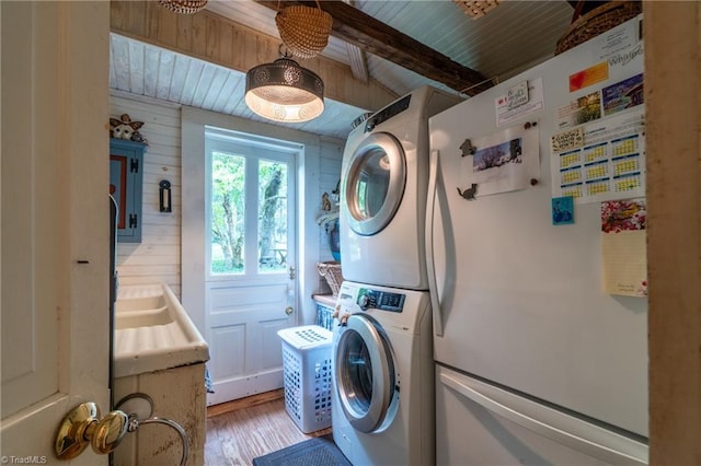 clothes washing area featuring wood-type flooring, wood ceiling, stacked washer / dryer, and wood walls