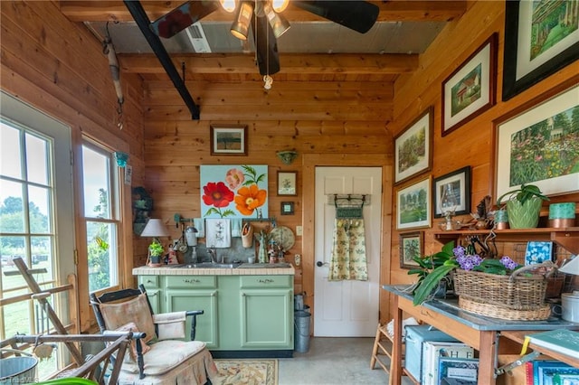 interior space with ceiling fan, sink, wood walls, and beam ceiling