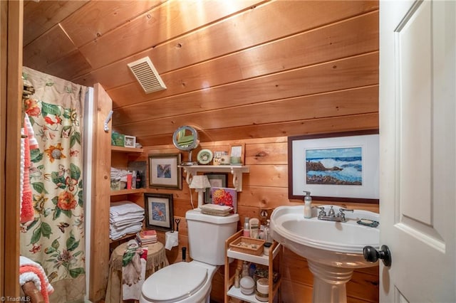 bathroom with wooden ceiling, wooden walls, toilet, and a shower with shower curtain