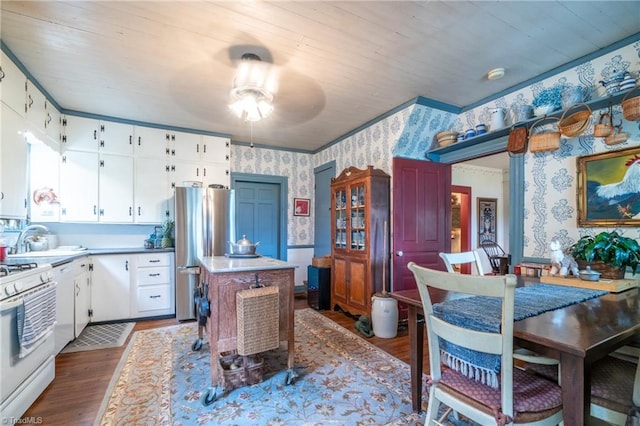 kitchen featuring ceiling fan, white cabinetry, stainless steel refrigerator, hardwood / wood-style flooring, and white range oven