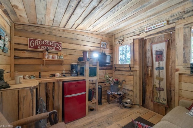 interior space with light hardwood / wood-style flooring, wood walls, and wooden ceiling