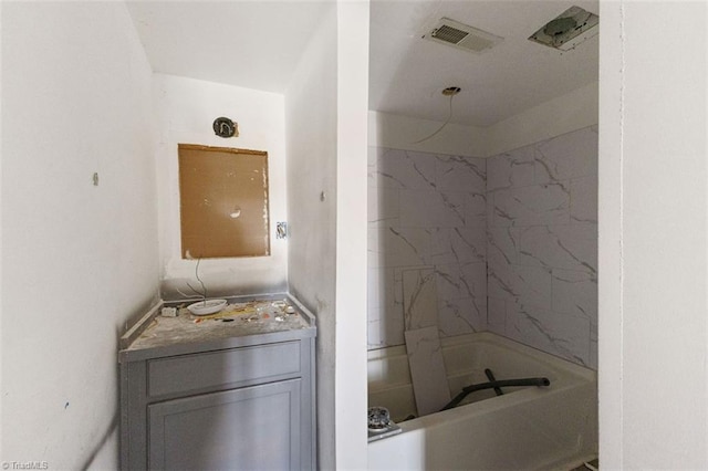 bathroom with washtub / shower combination, vanity, and visible vents